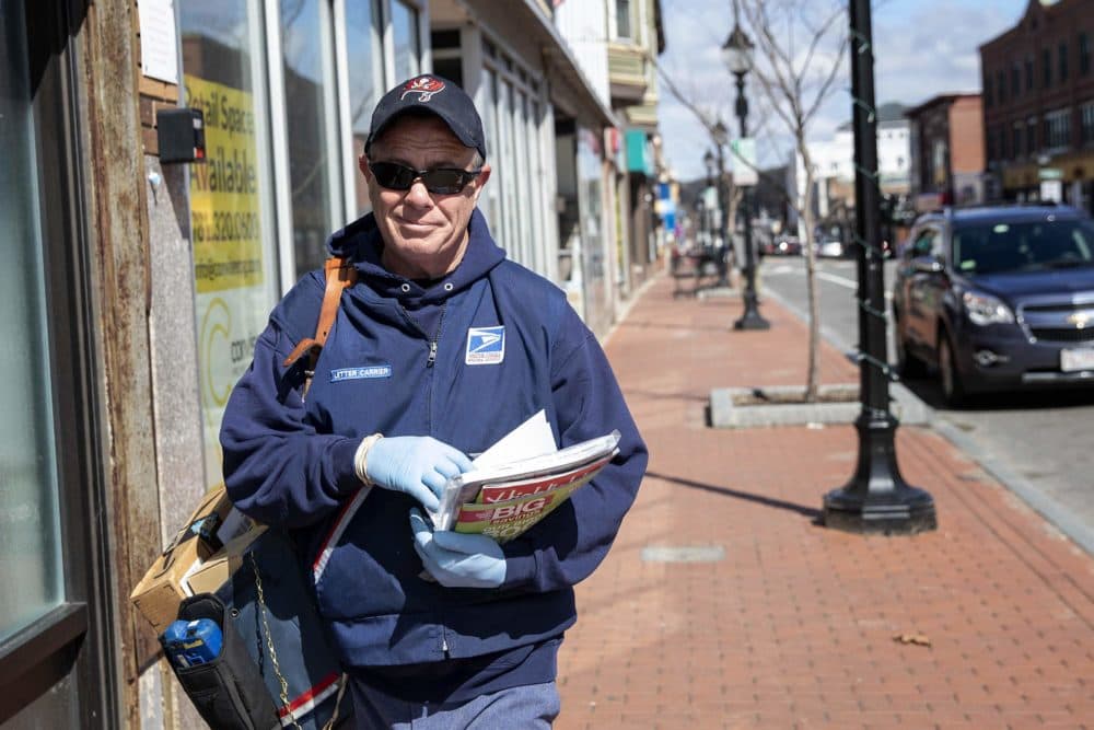 USPS letter carrier Chris Kirk walks down Moody Street in Waltham delivering mail. (Robin Lubbock/WBUR)