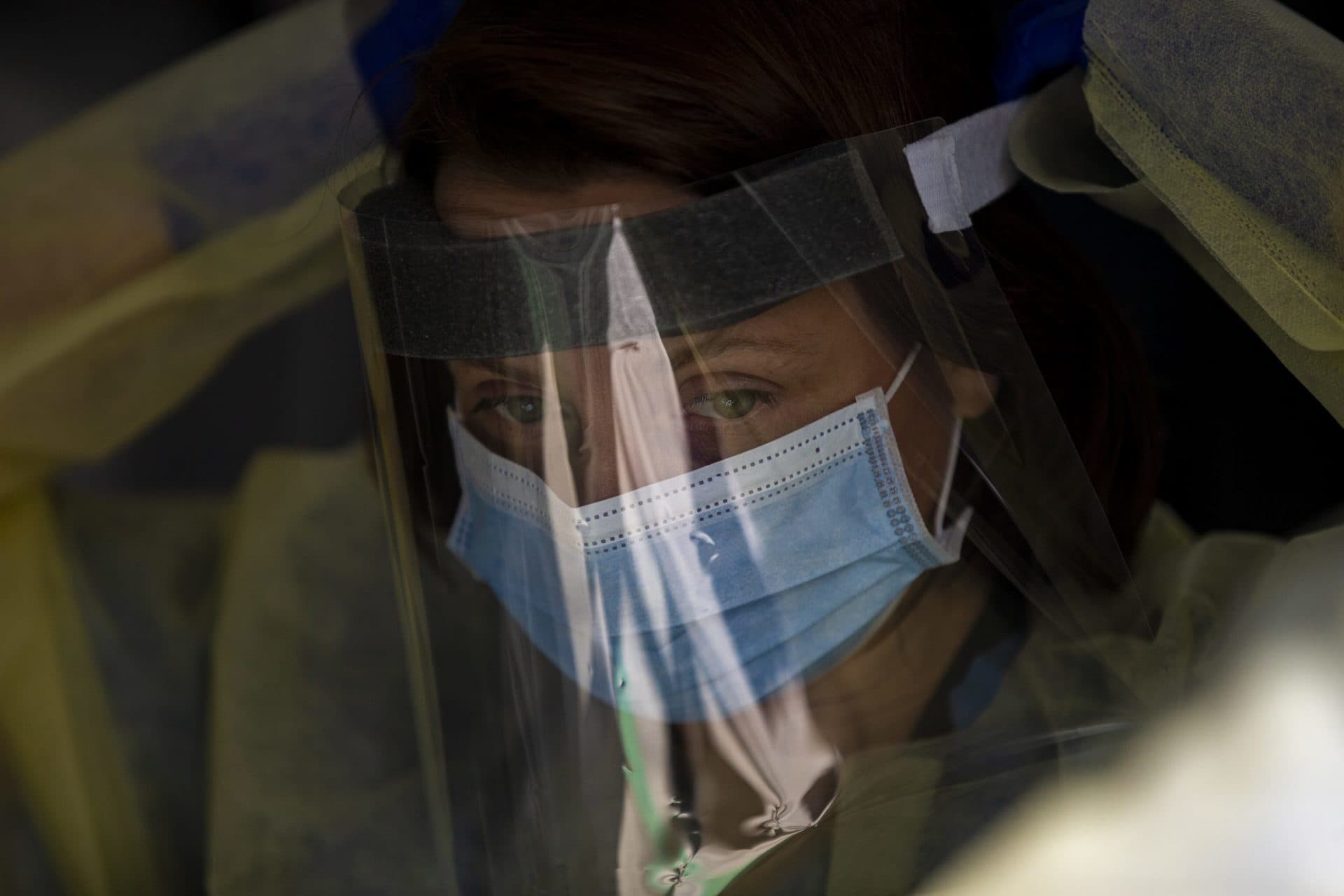 April 16: Dr. Melissa Nass of Boston Medical Center prepares for an examination by fitting on a face shield. (Jesse Costa/WBUR)