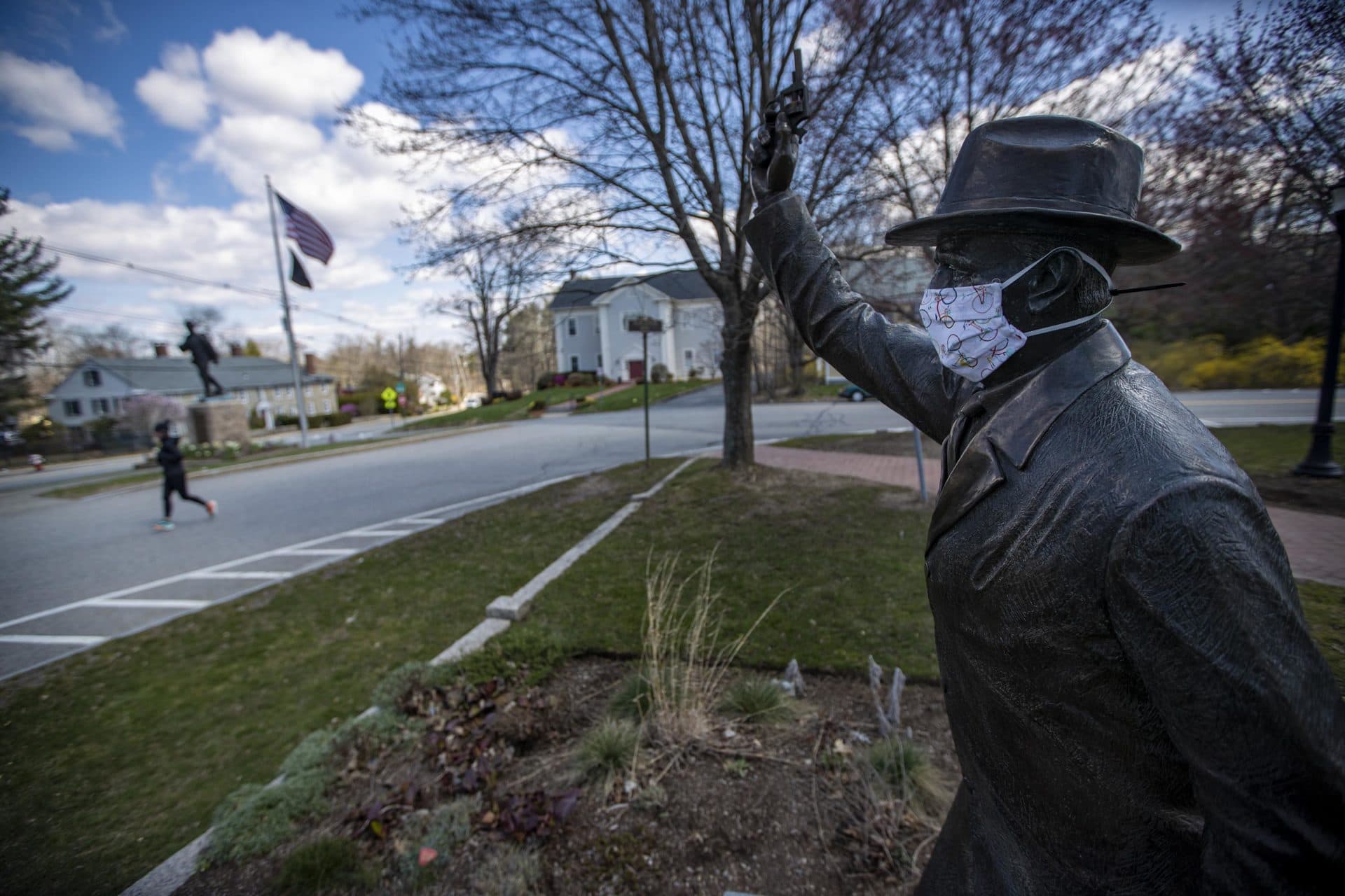 April 17: As she performs a virtual half marathon to keep up her training for September, Hopkinton resident Joy Donohue runs past “The Starter” statue in the Hopkinton Town Common, site of the start of the Boston Marathon. (Jesse Costa/WBUR)
