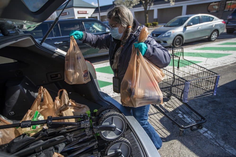 Woodford packs up the order she is fulfilling into her car in the parking lot of the Shaw’s Supermarket in Franklin. (Jesse Costa/WBUR)