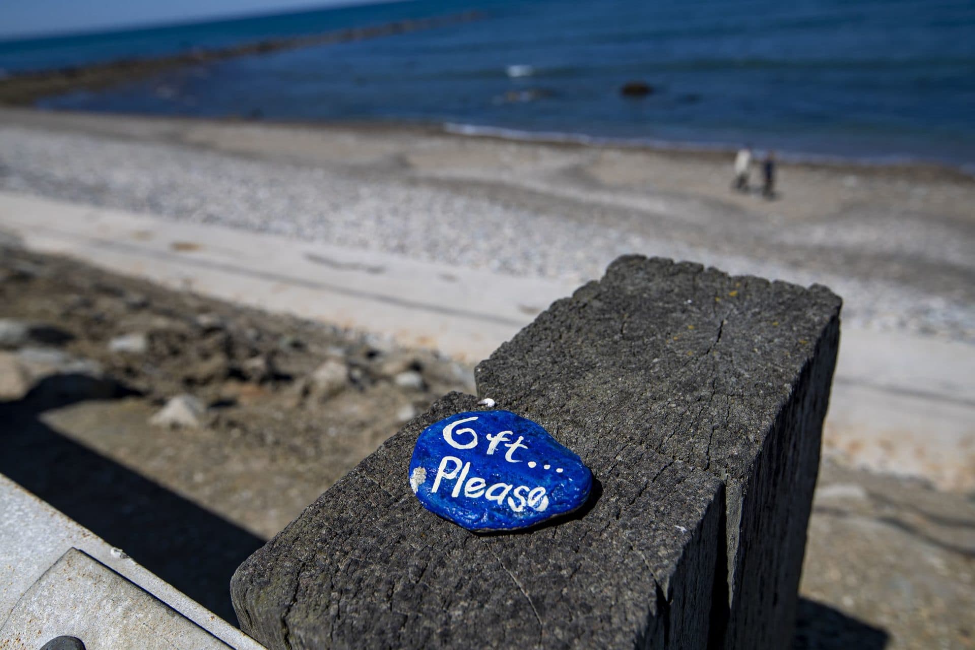 May 20: Brightly painted rocks with messages inscribed on them regarding the coronavirus pandemic are left on top of the guardrails at a virtually empty Brant Rock Beach in Marshfield. (Jesse Costa/WBUR)