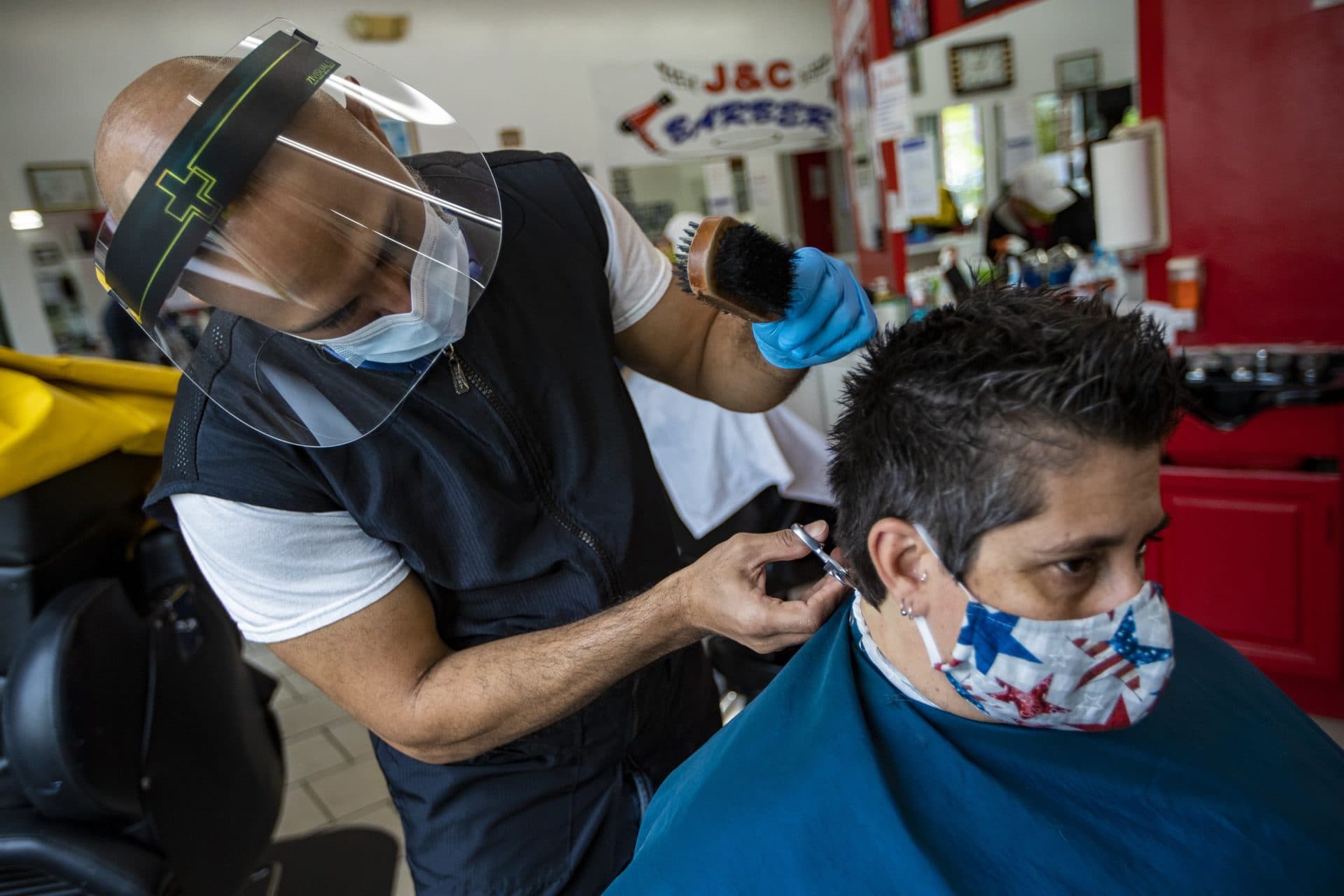 May 25: Leuris Luna gives a haircut to a customer at J&C Barber Shop in Roxbury, on the first day of reopening during the pandemic. (Jesse Costa/WBUR)