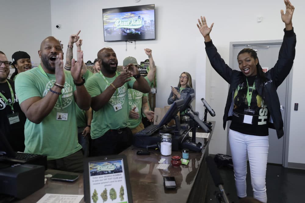 Entrepreneurs Kobie Evans, front left, and Kevin Hart, center left, celebrate the opening of Pure Oasis recreational marijuana shop with their first customer Niambe McIntosh, right, the moment the shop opened for the first time, Monday, March 9, 2020, in Boston. (Steven Senne/AP)