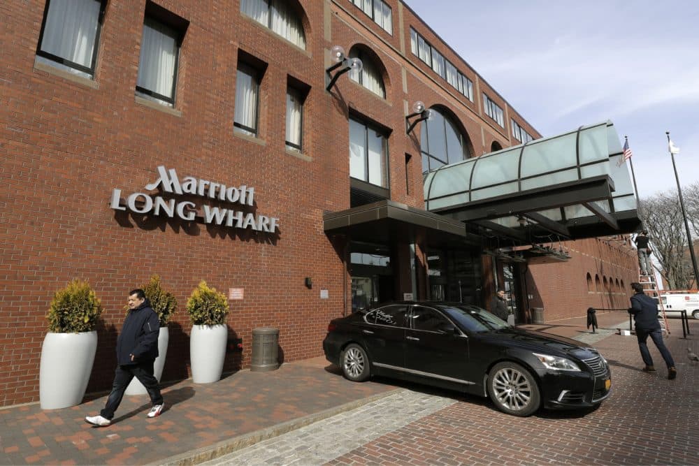 People walk outside the Marriott Long Wharf hotel, March 11, in Boston. Seventy of Massachusetts' first 92 confirmed coronavirus cases have been linked to a meeting of Biogen executives that was held at the hotel in late February 2020. (Steven Senne/AP)