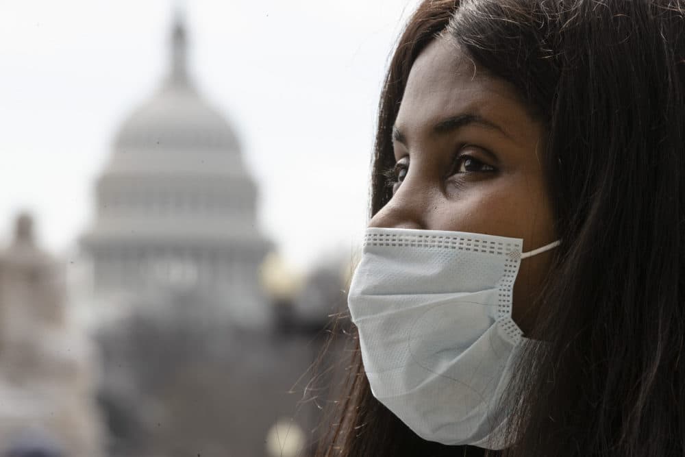 A woman wears a mask as she waits for a ride at Union Station, in view of the Capitol, Friday, March 13, 2020 in Washington. (Matt Rourke/AP)