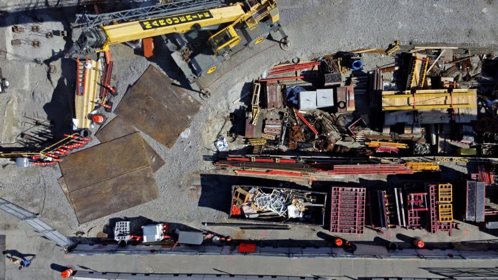 A pedestrian, at lower left, walks a dog past a construction site sitting idle after projects in the city were shut down due to the coronavirus in Boston. (David Goldman/AP)