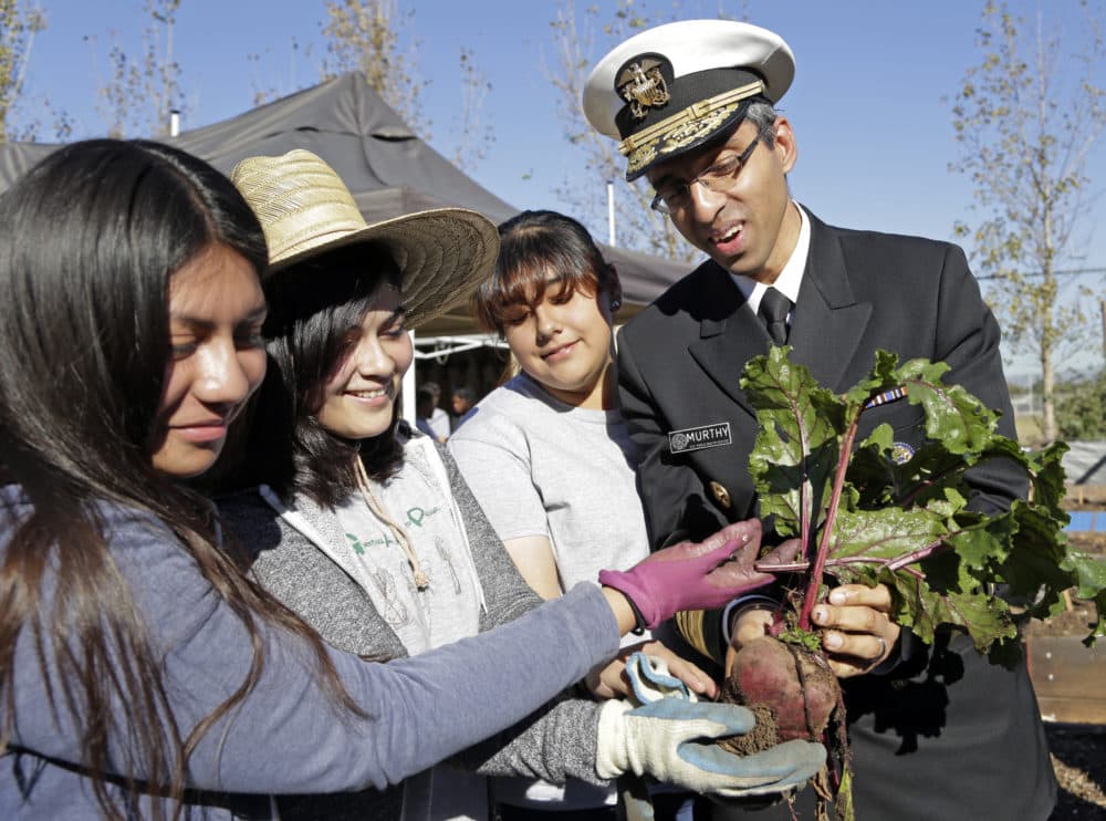 Former U.S. Surgeon General Vivek Murthy and John C. Fremont High School students hold a beet grown in the school's Gardening Apprenticeship Program plot on the campus south of downtown Los Angeles Friday, Nov. 20, 2015. (Nick Ut/AP Photo)