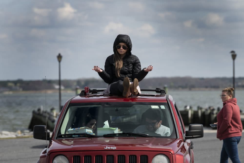 A member of Jesus' Church prays on top of a car during a Sunday church service held at Great Marsh Park in Cambridge, Maryland, on March 22, 2020. (JIM WATSON/AFP via Getty Images)
