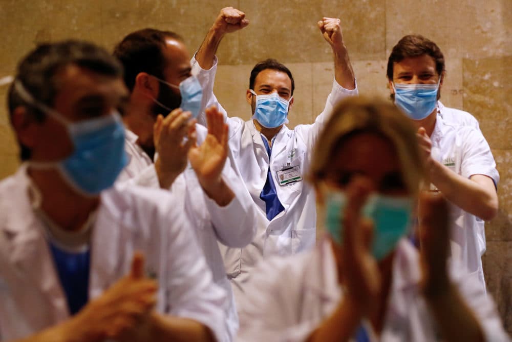 Healthcare workers dealing with the new coronavirus crisis in Spain, applaud in return as they are cheered on by people outside &quot;El Clinic&quot; University Hospital in Barcelona on March 26, 2020. (PAU BARRENA/AFP via Getty Images)