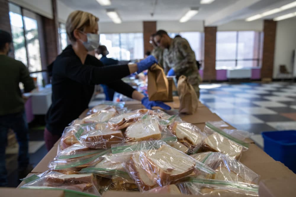 Volunteer Rhiannon Navin and U.S. National Guard troops put together meals for distribution to local residents at the WestCop community center on March 18, 2020 in New Rochelle, New York. New Rochelle has been a hot spot for the COVID-19 pandemic in the U.S. (John Moore/Getty Images)