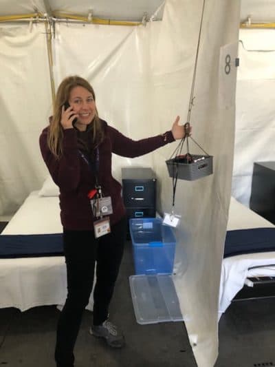 Dr. Jessie Gaeta, chief medical officer with the Boston Health Care for the Homeless Program, stands in one of the isolation tent patient "rooms" with a rigged holder a vital signs kit. (Martha Bebinger/WBUR)