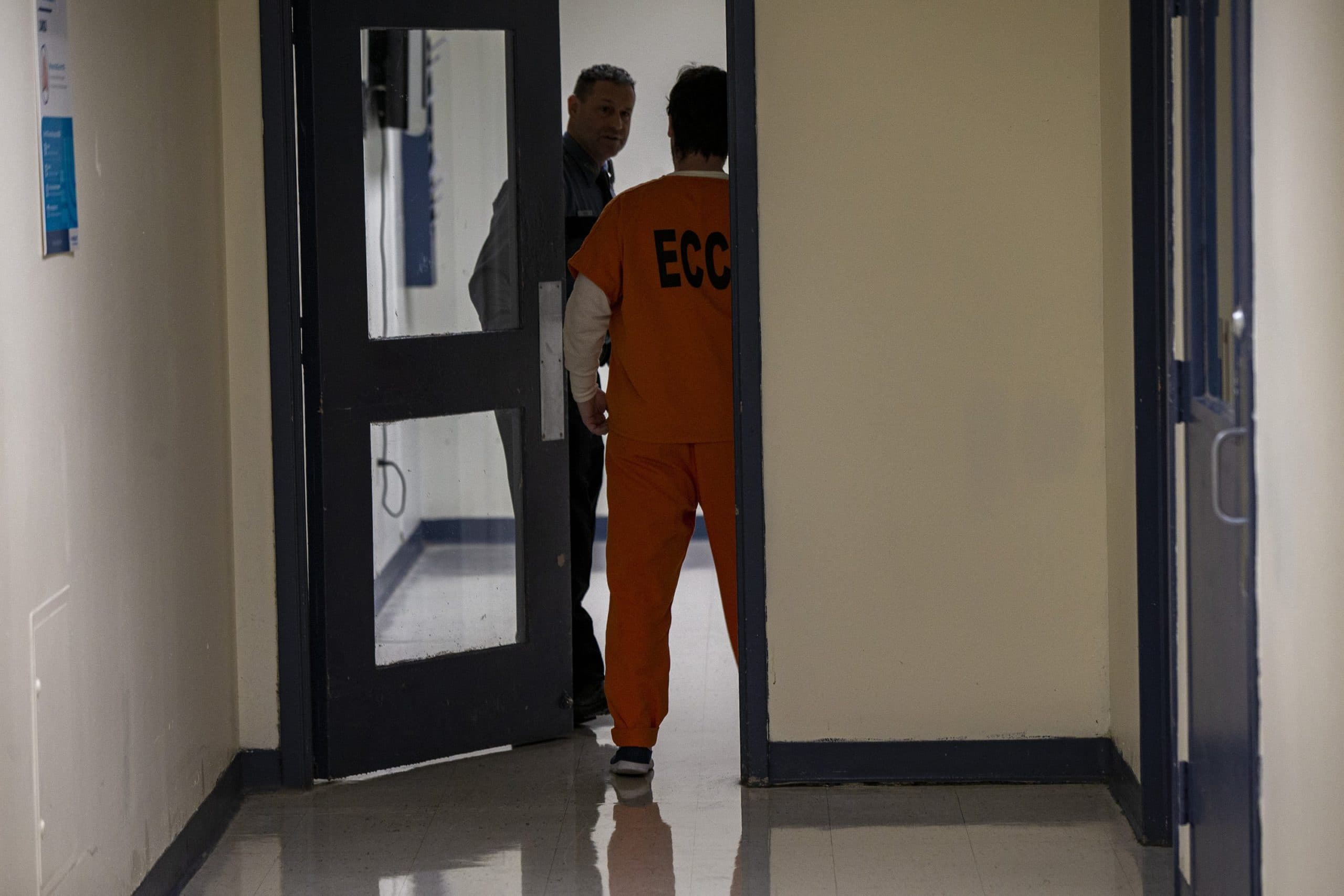 An Essex County jail corrections officer escorts an inmate through a hallway of the jail. (Jesse Costa/WBUR)