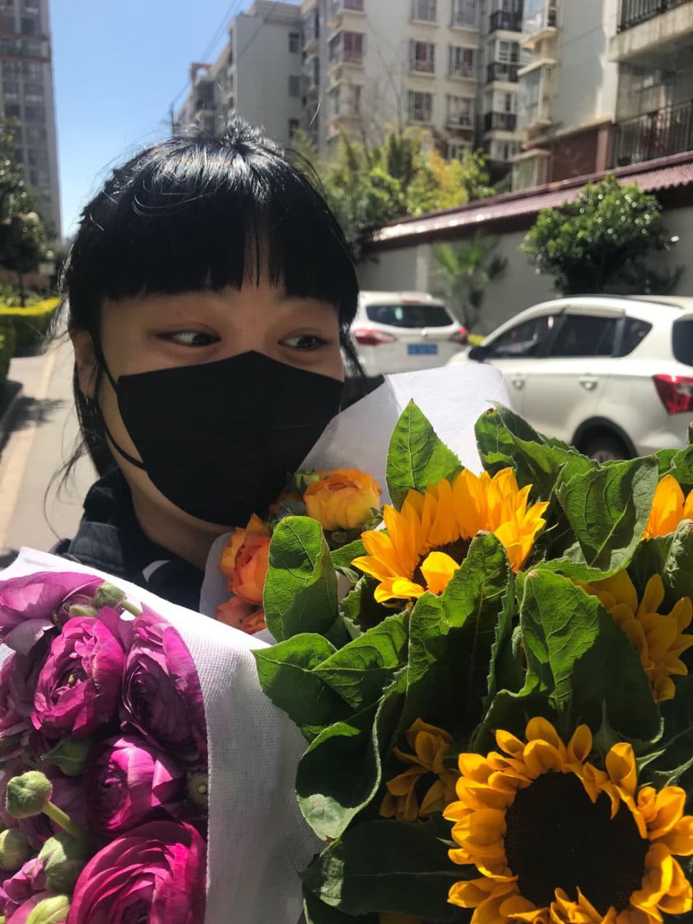 The author on March 1 with three bouquets of flowers from the wet market near her mother's apartment in Kunming, China.  (Courtesy)