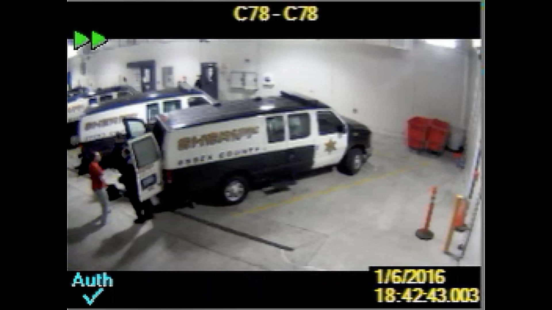 A screenshot from jail video shows Sam Dunn, in the red shirt, being loaded into a transport van to go to a Bridgewater treatment center. (Courtesy Essex County sheriff’s office)