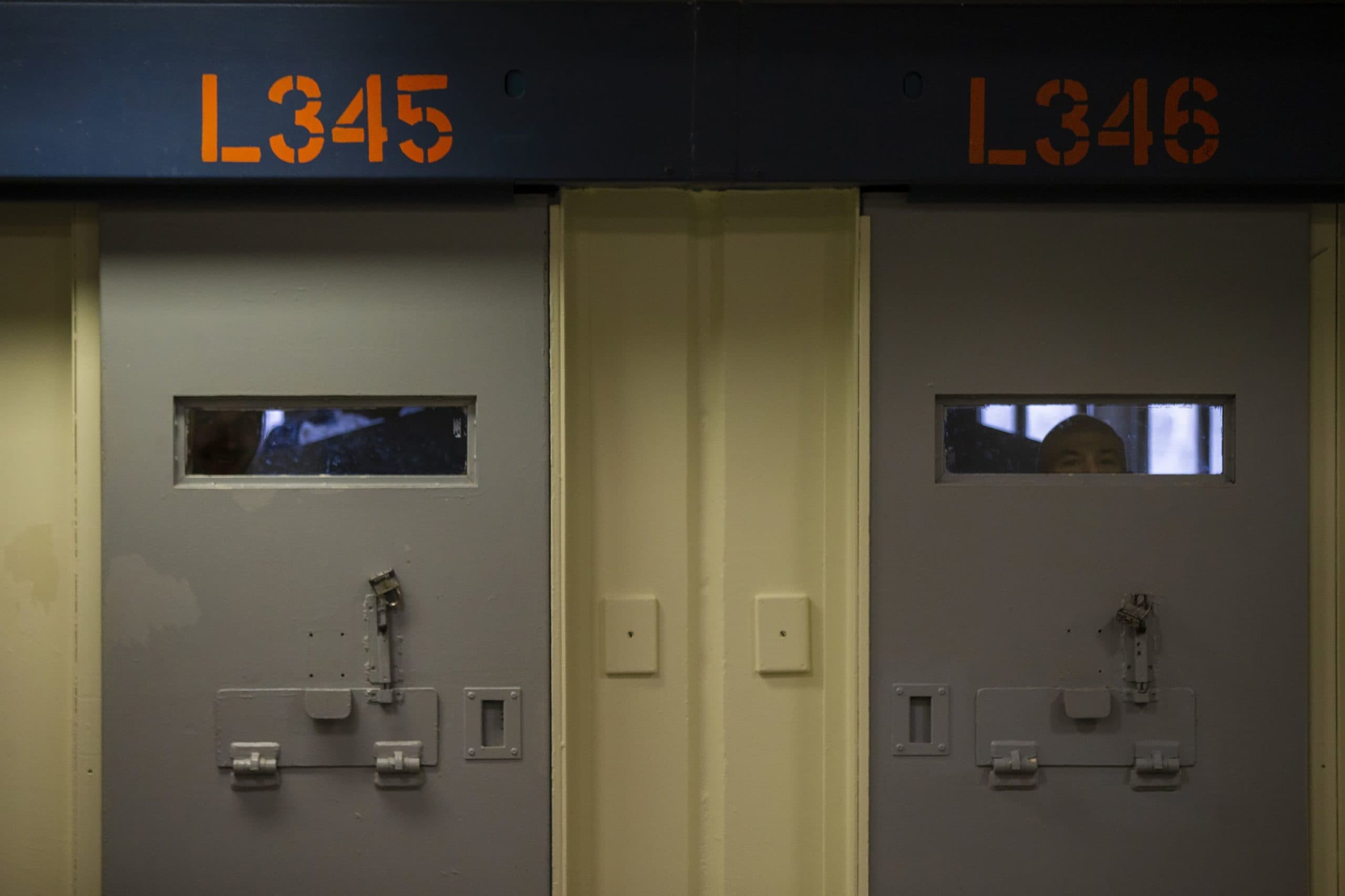 Inmates peer through the windows behind cell doors inside the Worcester County jail. (Jesse Costa/WBUR)