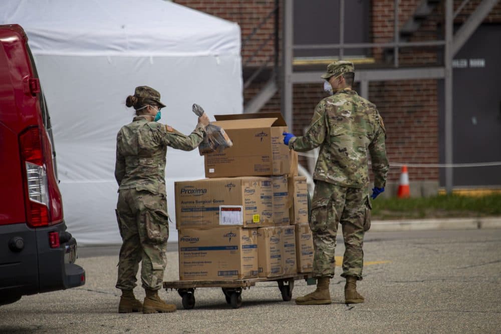 Following a coronavirus outbreak at the Soldiers' Home in Holyoke, members of the National Guard load boxes of protective gear onto a cart outside the facility on March 31. (Jesse Costa/WBUR)