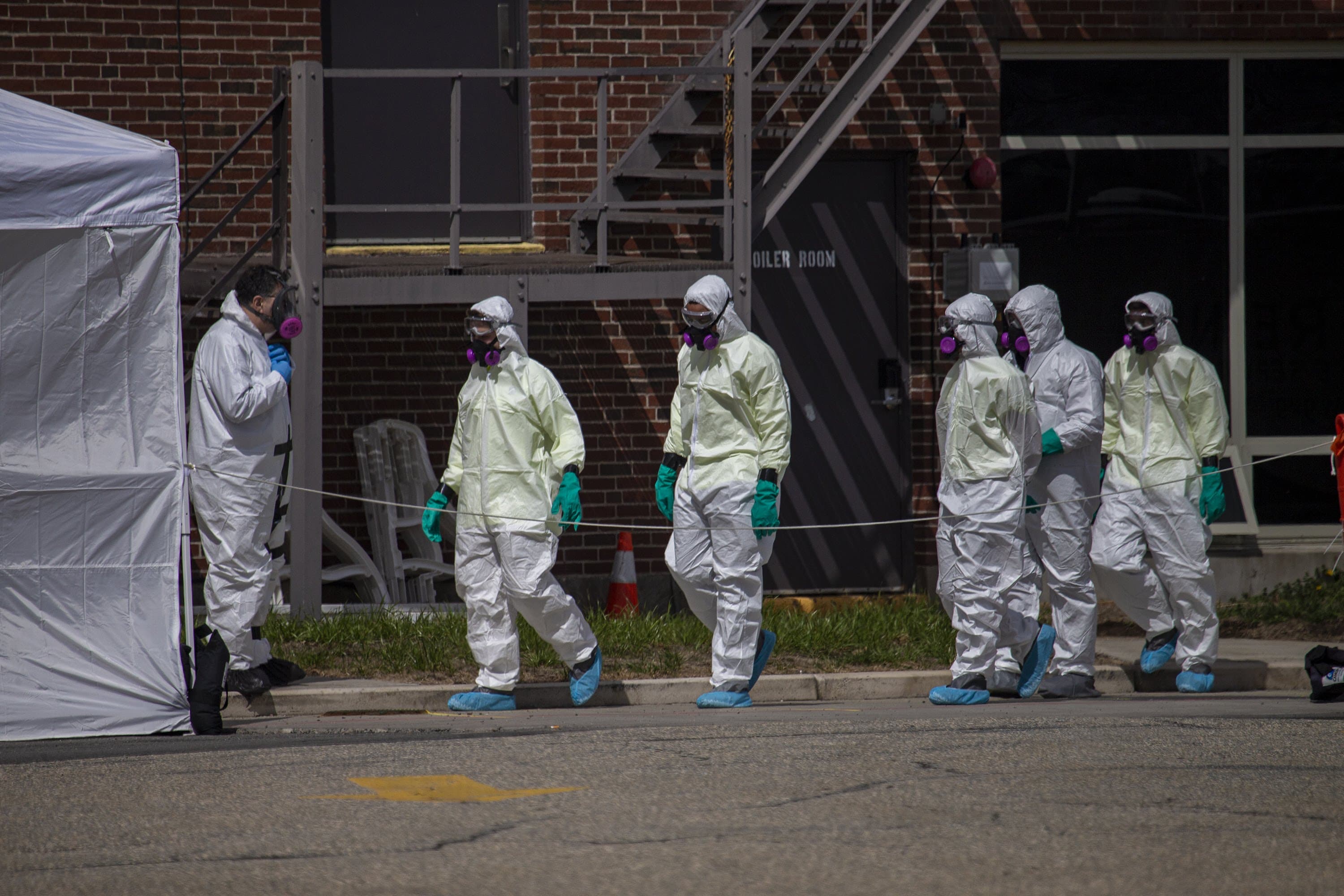 A cleaning crew suited up with protective gear enters the Soldiers Home on March 31. At least 18 veterans have died at the state-run long-term residence and health facility in Holyoke following a coronavirus outbreak. (Jesse Costa/WBUR)