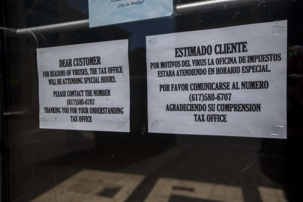 Signs on the front door of Taxes Financial Service, Inc. notifies patrons they will be open special hours during the pandemic. (Jesse Costa/WBUR)