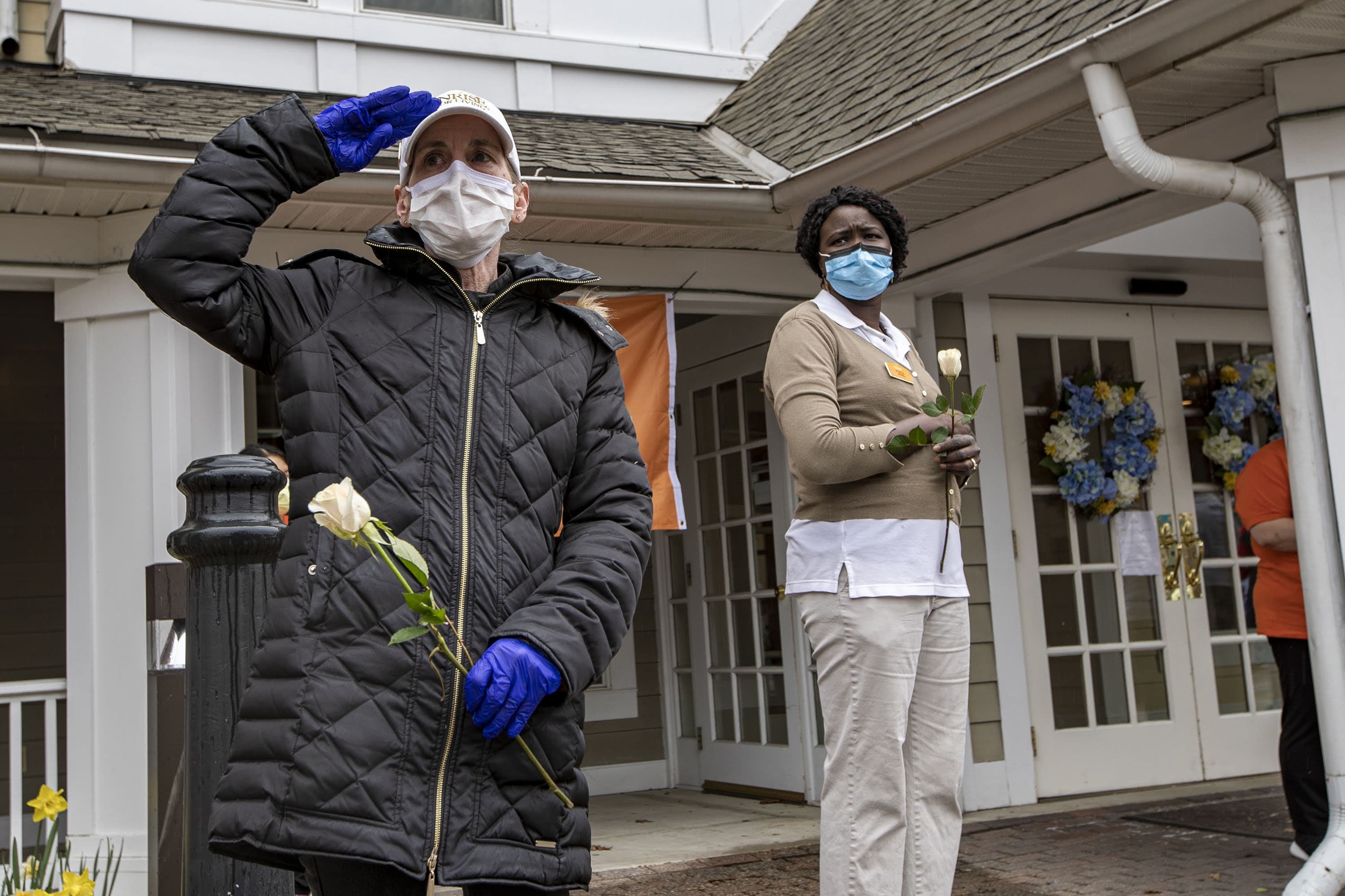 Longtime friend Cheryl Bento salutes as the hearse carrying Mary Foley’s body passes by Sunrise Senior Living in Arlington where Foley used to live. (Jesse Costa/WBUR)
