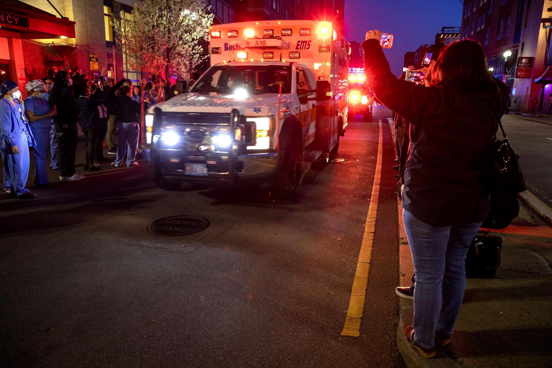 A Boston EMS vehicle with lights flashing drives by Tufts Medical Center in a show of support for healthcare workers. (Robin Lubbock/WBUR)