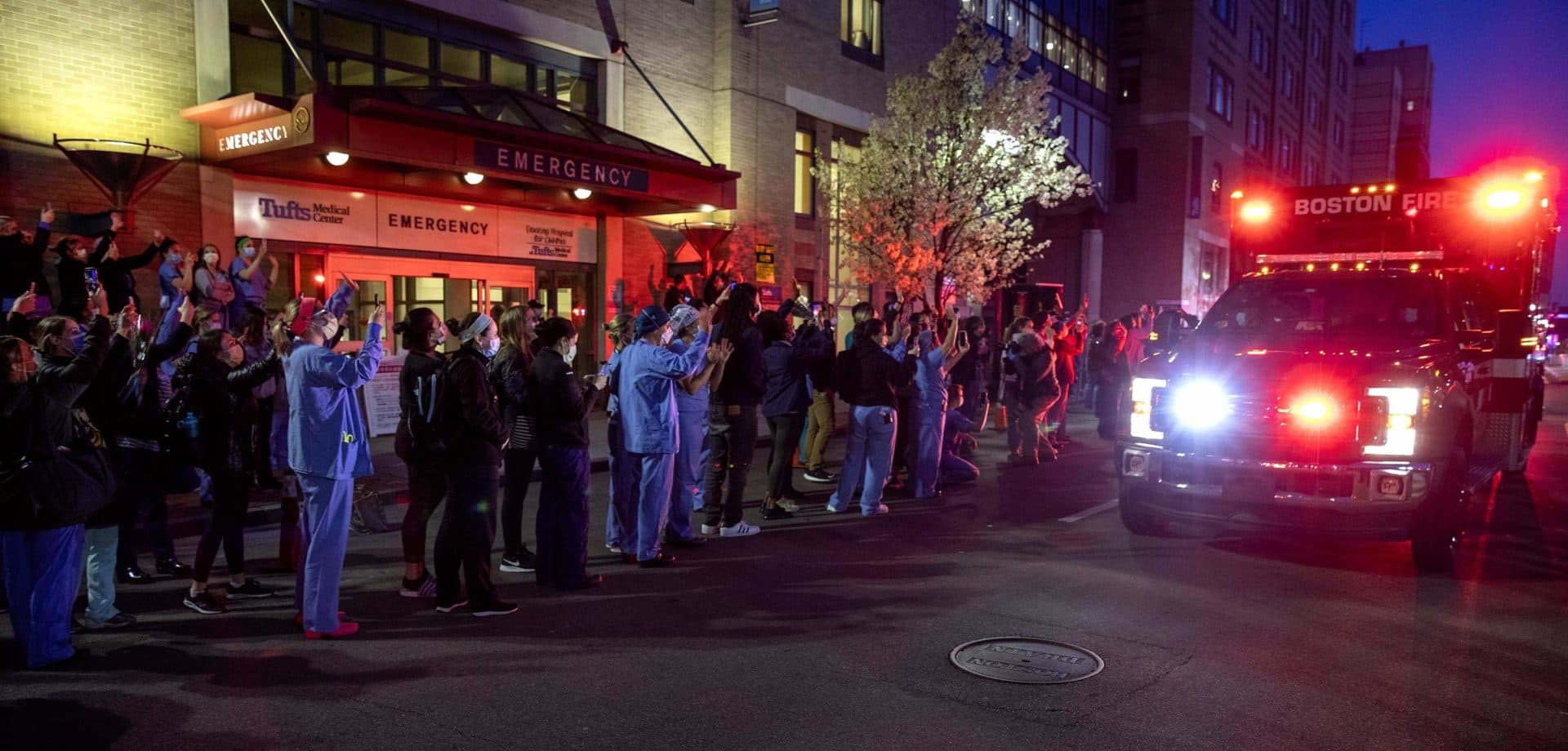 Boston emergency vehicles with lights flashing, drive by Tufts Medical Center in a show of support for healthcare workers. (Robin Lubbock/WBUR)