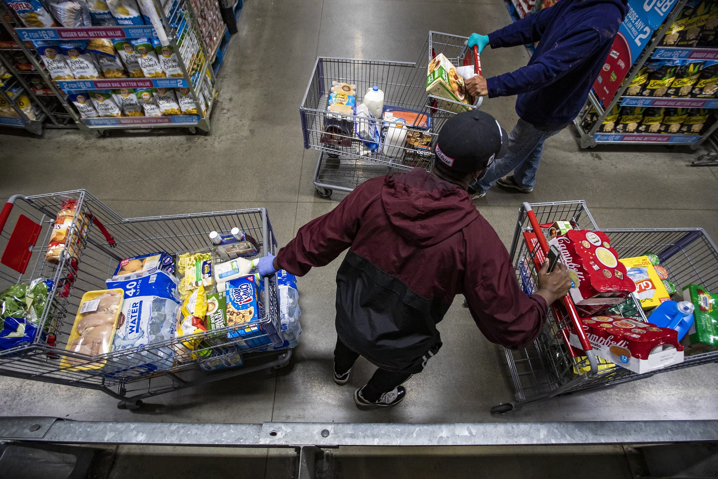 Instacart shopper Shamar Martin wheels two carts through an aisle at BJ’s Wholesale Club in Dedham, fulfilling three orders simultaneously. (Jesse Costa/WBUR)