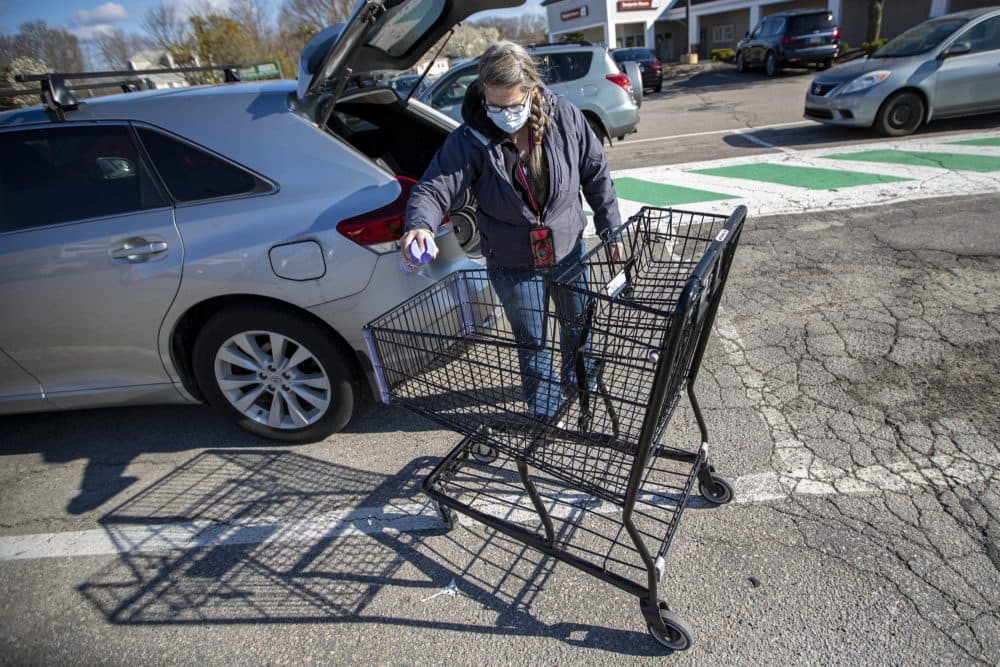Outside Shaw’s Supermarket in Franklin, Theresa Woodford sprays down a cart with Lysol disinfectant. (Jesse Costa/WBUR)