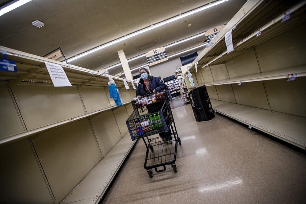 Instacart shopper Theresa Woodford wheels her cart past the empty shelves which normally are stocked with paper products at the Shaw’s Supermarket in Franklin. (Jesse Costa/WBUR)