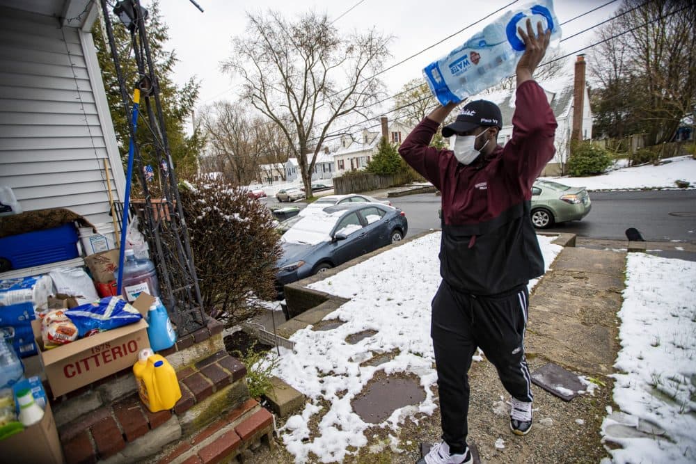 Martin leaves a delivery on the front steps of a home in Dedham. (Jesse Costa/WBUR)