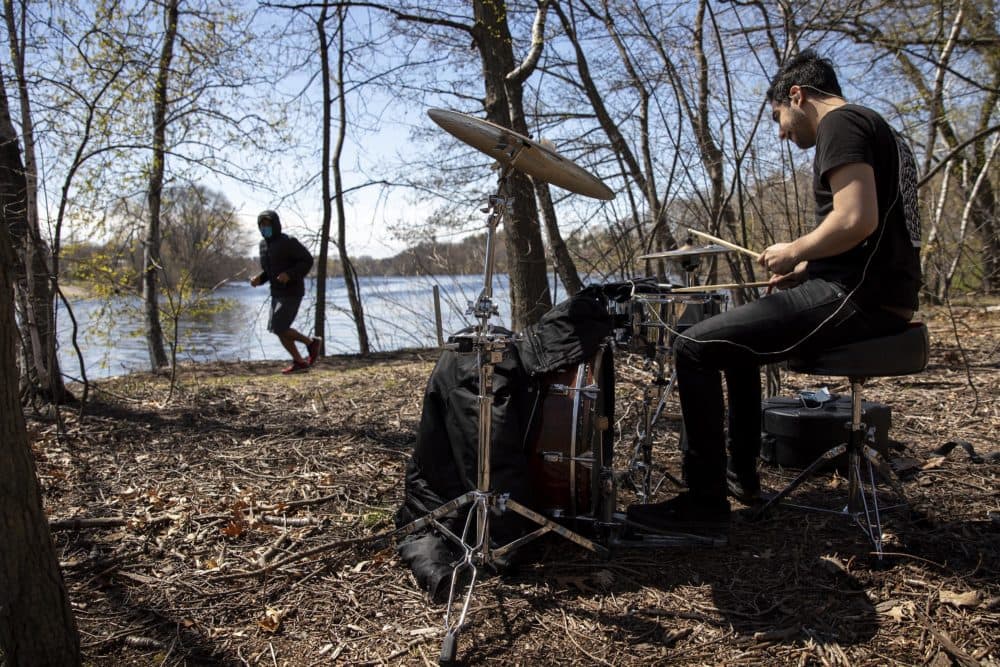 A runner along the Charles River sees Sander Bryce drumming in the woods. (Robin Lubbock/WBUR)
