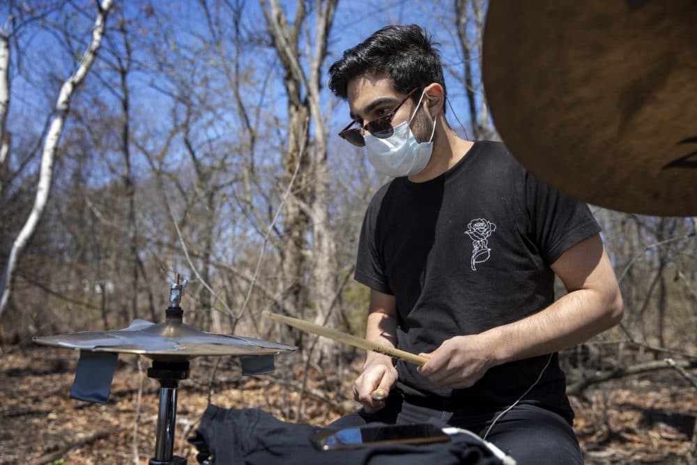 Drummer Sander Bryce, unable to practice at his usual studio, takes his drums to the woods by the Charles River to play. (Robin Lubbock/WBUR)