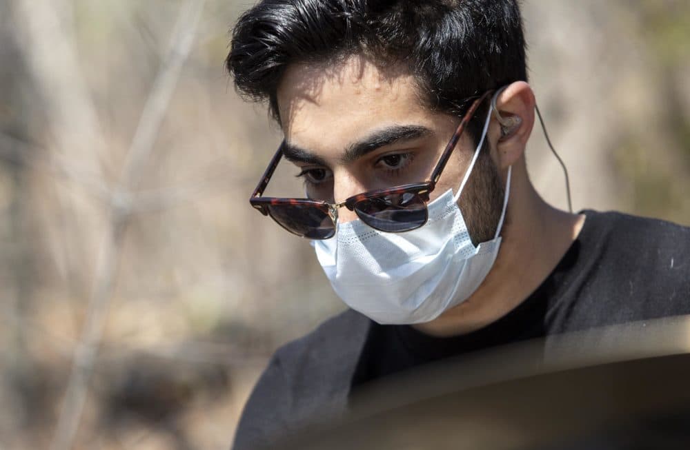 Wearing a mask to protect against COVID-19, drummer Sander Bryce practices in the woods by the Charles River. (Robin Lubbock/WBUR)