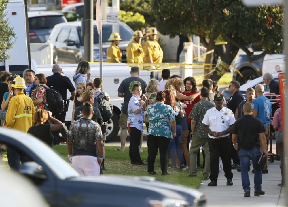 A group of Trader Joe's supermarket employees are reunited with their co-workers after a gunman barricaded himself inside the store in Los Angeles Saturday, July 21, 2018. (AP Photo/Damian Dovarganes)