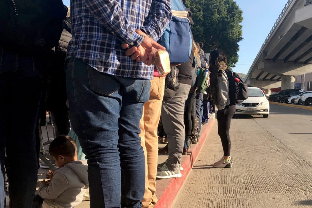 In this Wednesday, Jan. 8, 2020, photo people seeking asylum in the United States wait at the border crossing bridge in Tijuana, Mexico, just across the border from San Diego. (Elliot Spagat/AP)