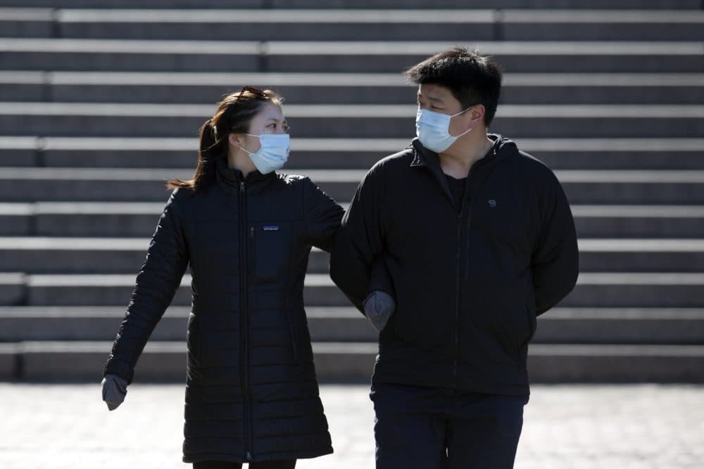 A couple wears protective masks while walking at Faneuil Hall, Saturday, April 4, 2020, in Boston. The new coronavirus causes mild or moderate symptoms for most people, but for some, especially older adults and people with existing health problems, it can cause more severe illness or death. (AP Photo/Michael Dwyer)