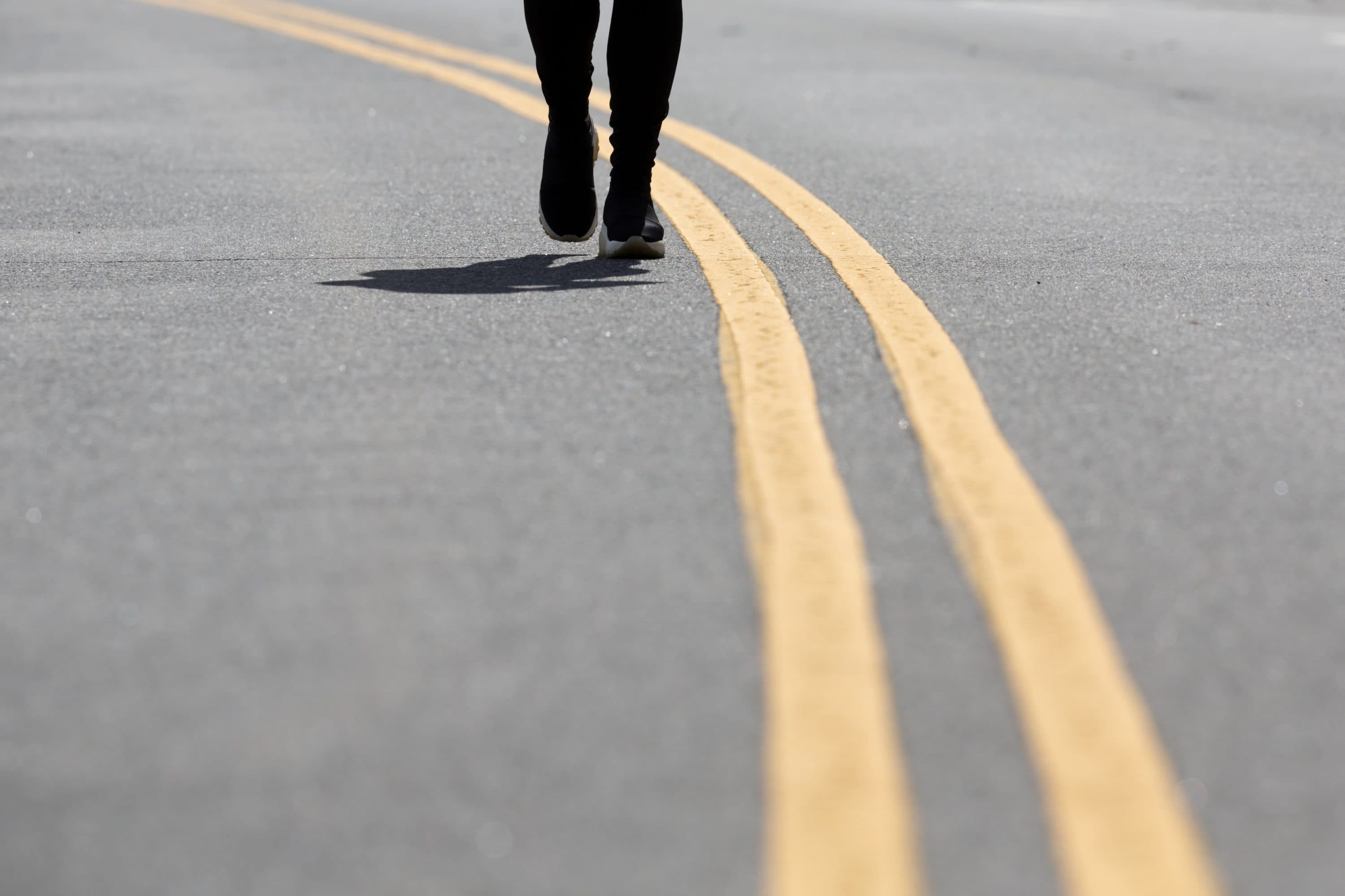 A person walks on Day Boulevard which has been closed to traffic to reduce crowding on the adjacent sidewalk and allow social distancing, Saturday, April 11, 2020, in Boston. (Michael Dwyer/AP)
