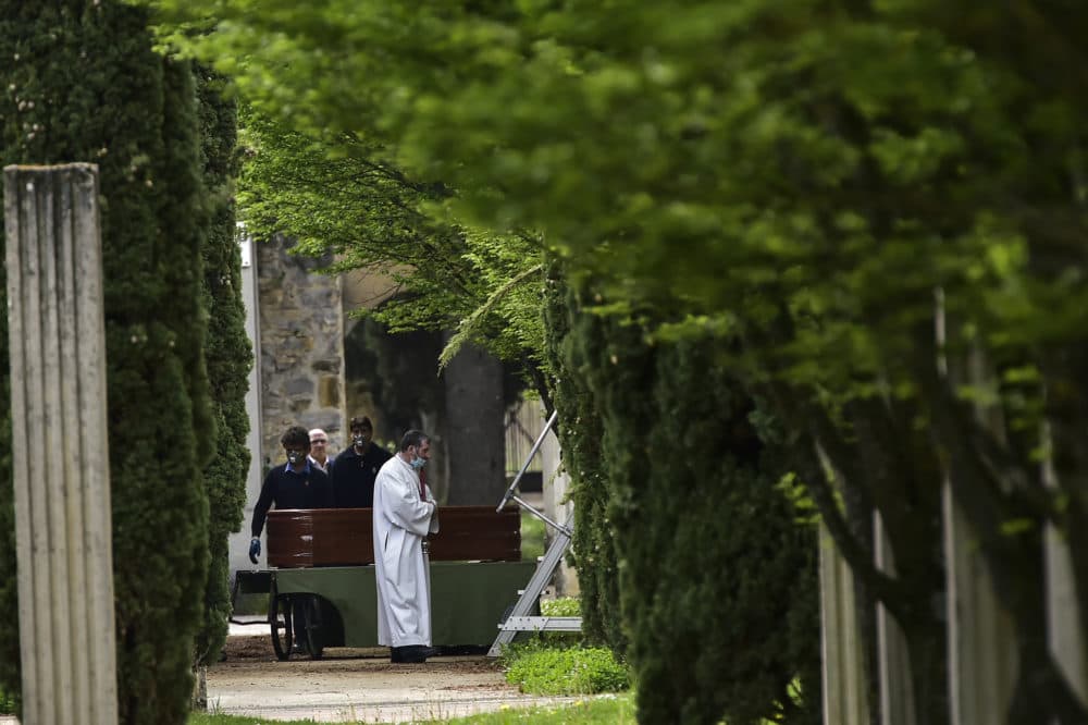 Undertakers and priest wearing masks to protect them from the coronavirus stand close to a coffin for a burial at San Jose Cemetery in Pamplona, northern Spain, Monday, April 13, 2020. (Alvaro Barrientos/AP)