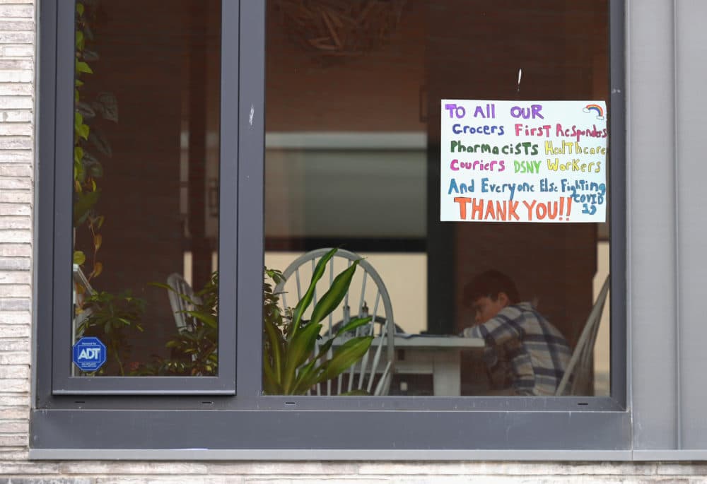 A child sits at a table in an apartment with a window sign thanking workers on March 25, 2020 in New York (Angela Weiss/AFP/Getty Images)