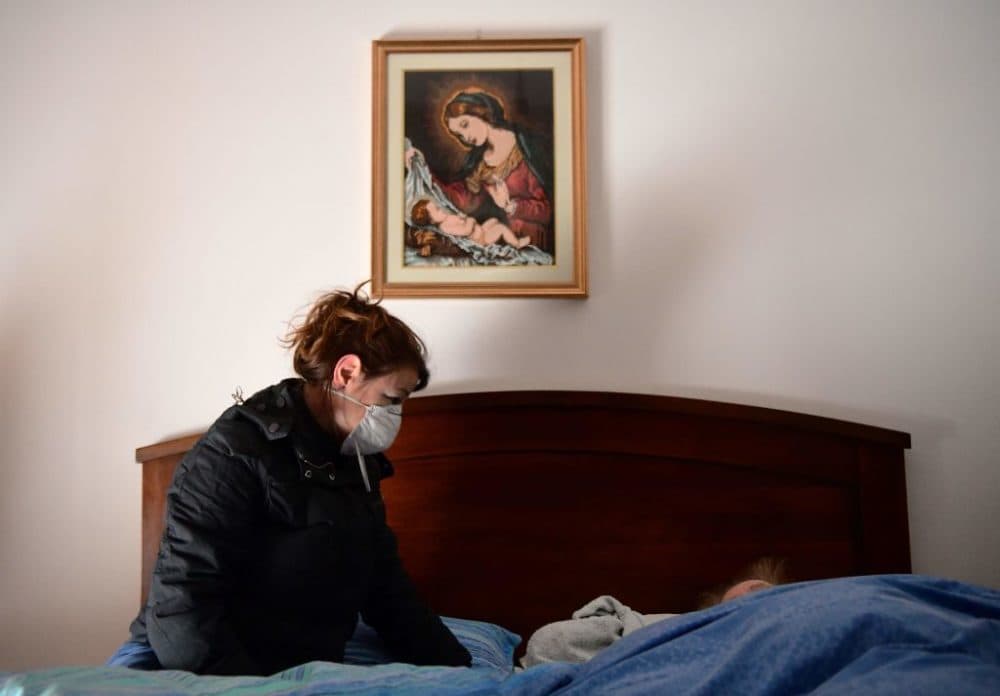 A woman talks to her 80-year-old mother, who is in bed with potential symptoms of COVID-19.(Piero Cruciatti/AFP/Getty Images)