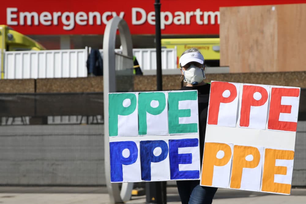 A demonstrator wearing a face mask holding signs reading &quot;PPE&quot; (personal protective equipment) protests about the lack of PPE for NHS nursing staff outside of a hospital in London. (Isabel Infantes/AFP/Getty Images)