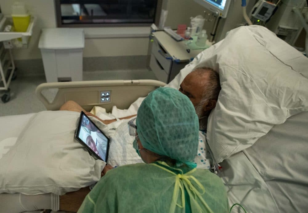 A nurse talks to the family of a patient using a tablet inside a negative pressure room on April 10, 2020, during her night shift in the intensive care unit exclusively for COVID-19 patients in Brussels. (Aris Oikonomou/AFP/Getty Images)