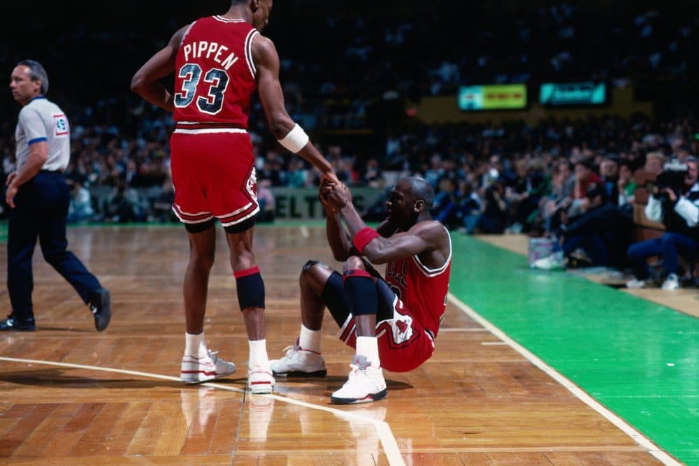 Scottie Pippen #33 helps Michael Jordan #23 up from the floor against the Boston Celtics during a game played in 1990 in Boston, Massachusetts. (Photo by Dick Raphael/NBAE via Getty Images)