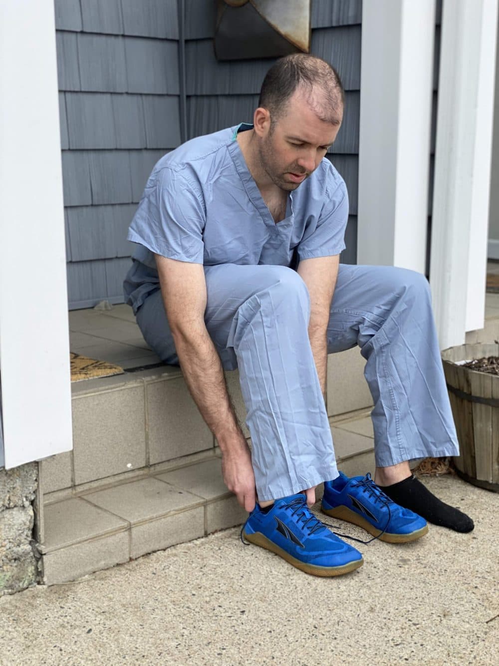 Joshua Merson, an emergency medicine physician assistant, takes his shoe and clothes off on their condo porch in Chelsea so that nothing contaminated comes into the house. (Courtesy Joshua Merson)