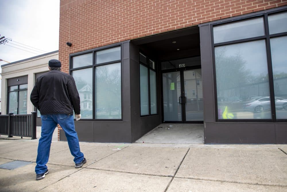 A man stops to look at shuttered Pure Oasis, a recreational cannabis shop which just opened in early March in Dorchester. (Jesse Costa/WBUR)