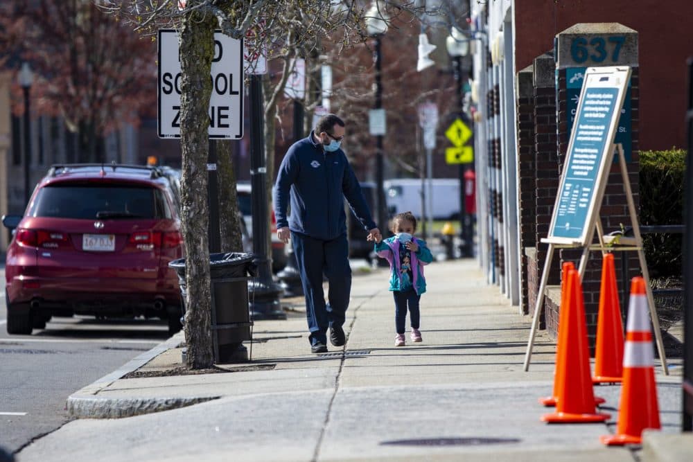 Un padre y su hija pequeña caminan por Washington Street en camino a Codman Square Health Center. (Jesse Costa/WBUR)