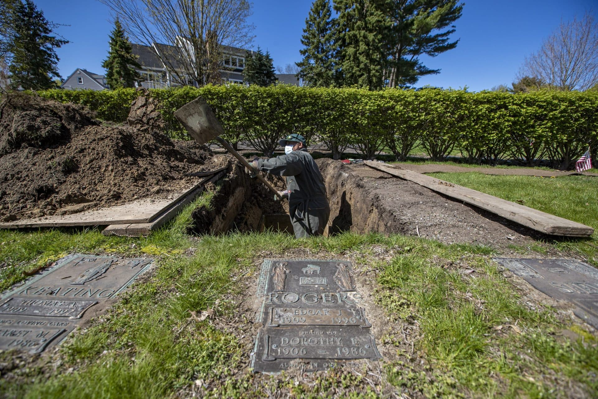 Roberto Arias digs out a grave site at Woodlawn Cemetery in Everett, one of 10 sites being prepared that day. (Jesse Costa/WBUR)
