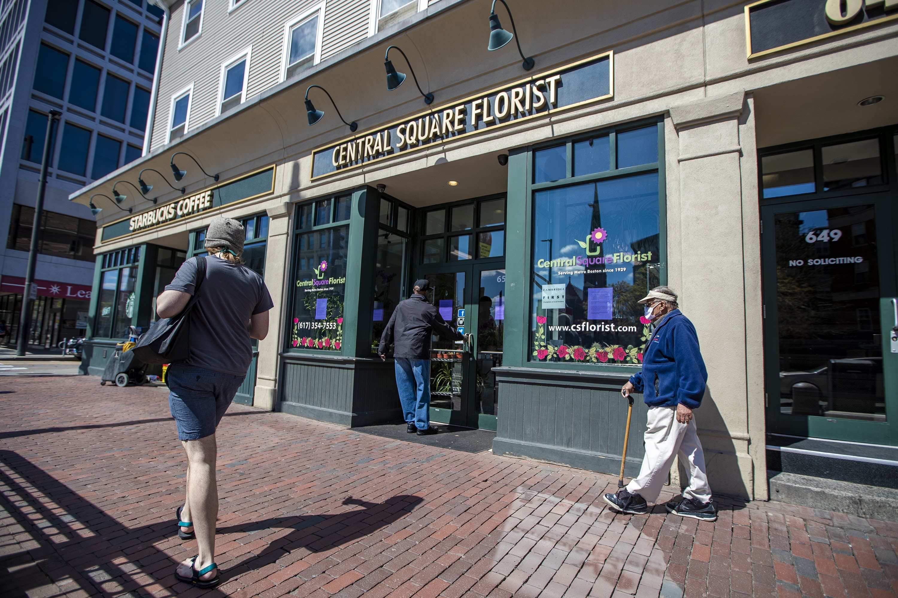 A prospectve patron attempts to open the front door of Central Square Florist in Cambridge, which is not open for in-store or curbside business, but only for contactless delivery, now that the COVID-19 restrictions for some non-essential businesses in Massachusetts have been lifted. (Jesse Costa/WBUR)