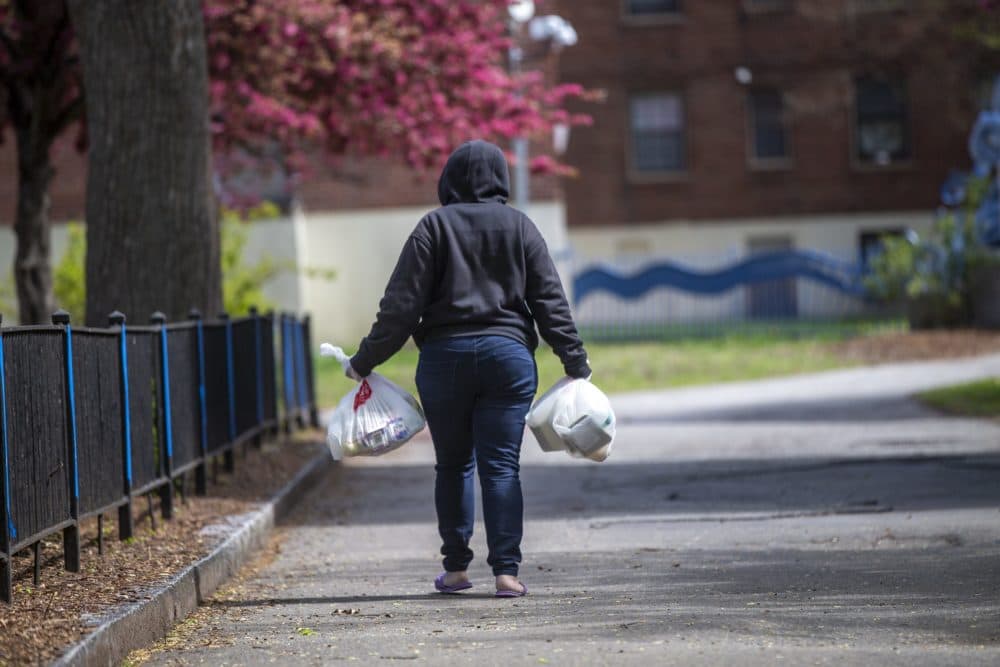 A woman heads home with meals she picked up at a meal distribution site on a BHA property. (Jesse Costa/WBUR)