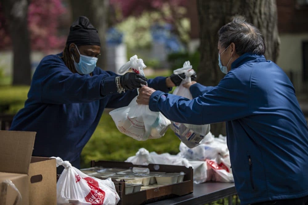 BHA employee Bonnie Jones hands meals to a man at the Mary Ellen McCormack development in South Boston. The program put together by city leaders and nonprofit partners to respond to the pandemic has distributed more than 1.1 million meals since mid-March. (Jesse Costa/WBUR)