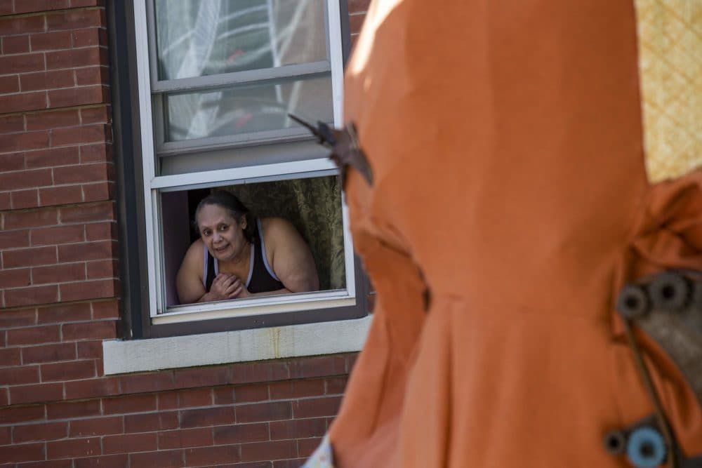 Chelsea resident Mildred Santos looks at the Corona/Crown Art Project as it sits outside her apartment window on 4th Street. (Jesse Costa/WBUR)
